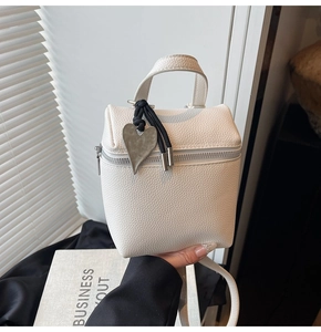 Dettaglio della mini borsa bianca con trama in pelle litchi e pendente a forma di cuore