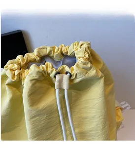Close-up of yellow drawstring closure with white woven cords and metal eyelets on backpack
