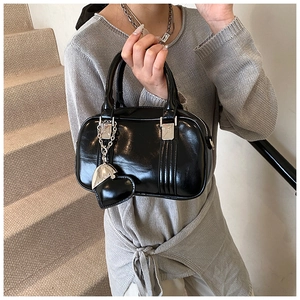 Detail of glossy black bowling bag with silver heart pendant and chain accessory