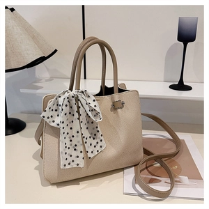 Détail du sac à main tissé beige avec foulard à pois et bandoulière réglable sur bureau minimaliste