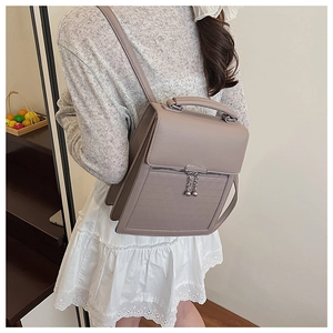 Detail of taupe faux leather backpack featuring silver sphere zippers and top handle style