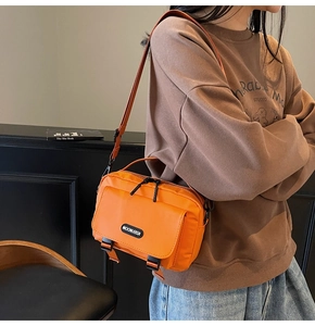 Detail of bright orange waterproof nylon messenger bag with buckle and brand logo