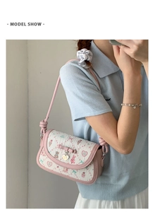 Detail of pink balletcore crossbody bag with cartoon prints and a heart charm on model
