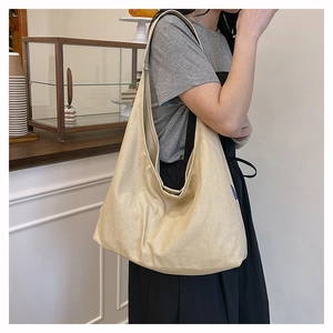 Side view of large apricot canvas tote bag on model in cozy cafe setting