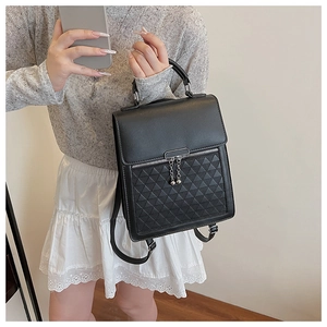 Detail of black geometric quilted backpack with silver metal bar and chain accent