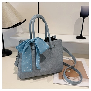 Détail d'un sac cabas bleu clair texturé avec foulard en soie à pois et bandoulière