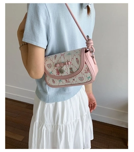 Detail of pink bow and engraved heart pendant on cute printed crossbody bag