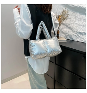 Sac fourre-tout argenté matelassé avec large bandoulière porté par un mannequin chic