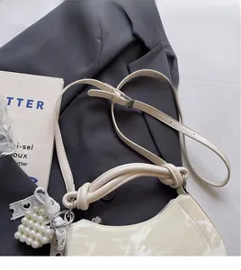 Detail of cream white dumpling bag with pearl heart pendant and knotted handle design