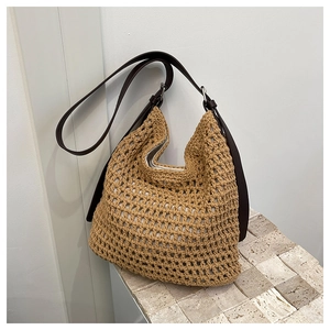 Détail du sac seau tissé en paille kaki avec bandoulière en cuir brun et maille ajourée