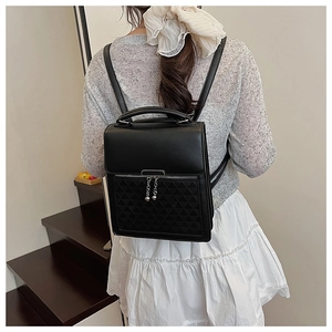 Close-up of black leather bag featuring geometric triangle embossed pocket and silver chain