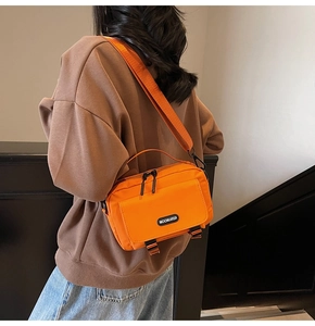 Detail of bright orange nylon messenger bag showing durable texture and broad shoulder strap