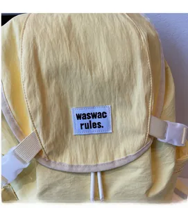 Detailed macro shot of pale yellow backpack fabric texture and white branded woven label