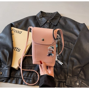 Détail du sac à bandoulière rose en cuir grainé avec breloque chien et bandoulière