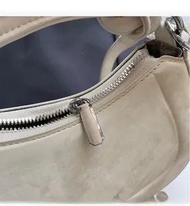 Macro shot of silver metal zipper detail on off-white textured leather shoulder bag