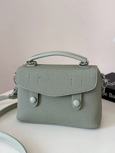 Mint green textured crossbody bag with top handle and matching strap on neutral background