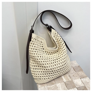 Détail du sac à bandoulière tissé crème avec bandoulière en cuir brun et boucle métallique