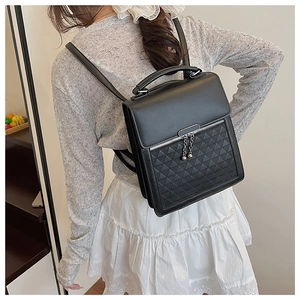 Detail of black structured faux leather handbag with geometric embossed triangle pattern