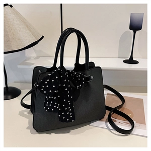 Détail du sac seau noir à texture tressée avec foulard à pois et bandoulière réglable