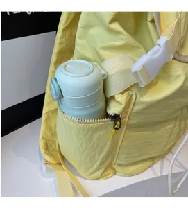 Detail view of a yellow nylon backpack side pocket featuring a zipper and a water bottle