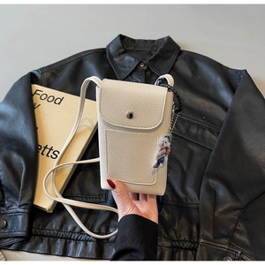 Détail du sac de téléphone blanc en cuir grainé avec boucle et breloque chiot