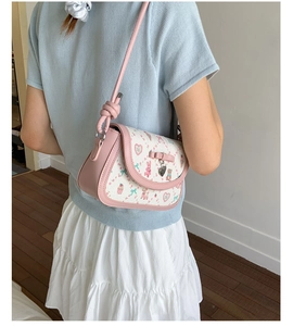 Pink and white crossbody bag with cute animal prints and bow charm shown on model