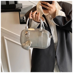 Close-up of silver bowling handbag with heart charm accessory and metallic finish texture