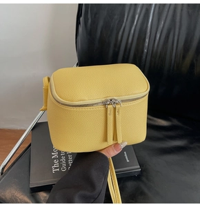 Detail der leuchtend gelben Würfel-Umhängetasche mit Leder in Litschi-Optik und Silberzipper