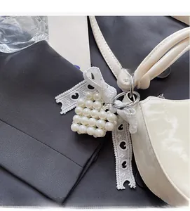 Detail of white heart pearl charm with lace ribbon attached to a handbag handle