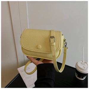 Close-up of the light yellow crossbody bag featuring fine lychee leather texture and silver buckle