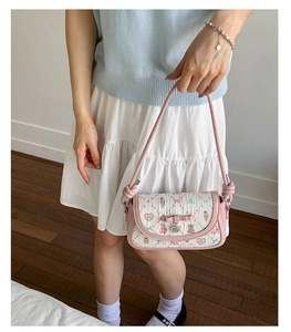 Detailed view of pink bow decoration and heart charm on printed floral square crossbody bag