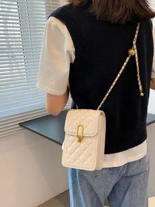 White quilted crossbody bag with gold chain strap shown on model for a stylish look