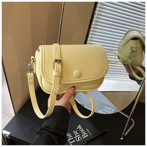 Detail of pale yellow crossbody bag featuring pebble leather texture and a round clasp