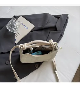 Internal view of a white crescent shoulder bag showing capacity for phone and makeup