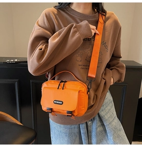 Close-up of bright orange nylon crossbody bag with black buckles and adjustable strap