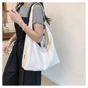 Close-up of a large white canvas tote bag showing soft natural texture and blue side label