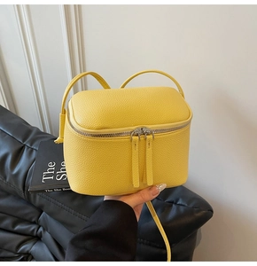 Detaillierte Makroansicht der leuchtend gelben Mini-Tasche aus Leder mit silbernem Reißverschluss