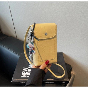 Détail du sac de téléphone jaune à texture litchi avec pendentif chien et boucle en métal