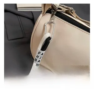 Détail du sac polochon en nylon crème avec fermeture éclair et sangle décorative