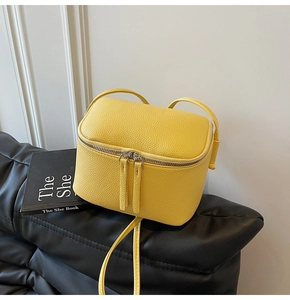 Detail der gelben Mini-Box-Tasche aus strukturiertem Leder mit silbernem Doppel-Reißverschluss