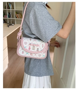 Detail of pink bow and heart pendant on a cute cartoon pattern crossbody bag