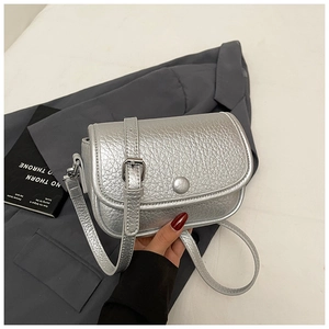 Detail of silver litchi grain texture on crossbody saddle bag with adjustable strap