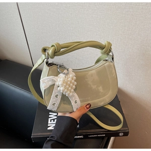 Detail of light green crescent bag with pearly heart charm and knotted strap