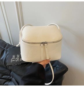 Detailansicht der weißen Mini-Umhängetasche aus Leder mit Lychee-Muster und Silberzipper