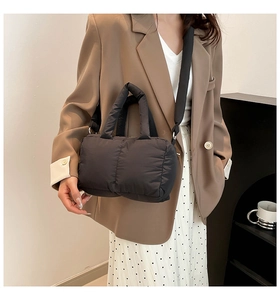 Détail d'un sac cabas matelassé noir avec une large bandoulière porté par un mannequin