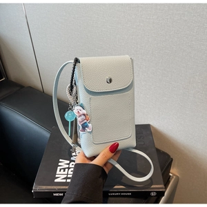 Gros plan du sac de téléphone en cuir bleu clair avec breloques de dessin animé