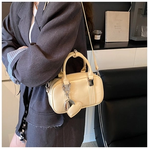 Detail of light yellow bowling bag with silver heart charm and crossbody strap