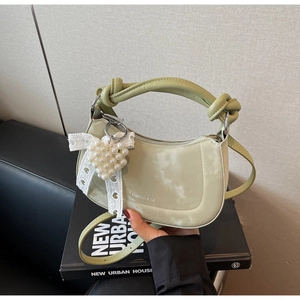 Light green hobo bag featuring a knotted handle, white bow, and heart pearl charm detail