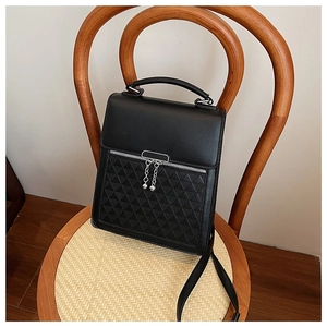 Detail view of black PU leather handbag with elegant triangular quilted pattern on a wooden chair