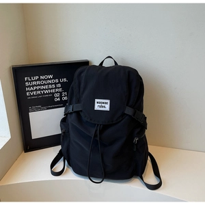 Detail of black canvas backpack showing the secure plastic buckles and drawstring closure